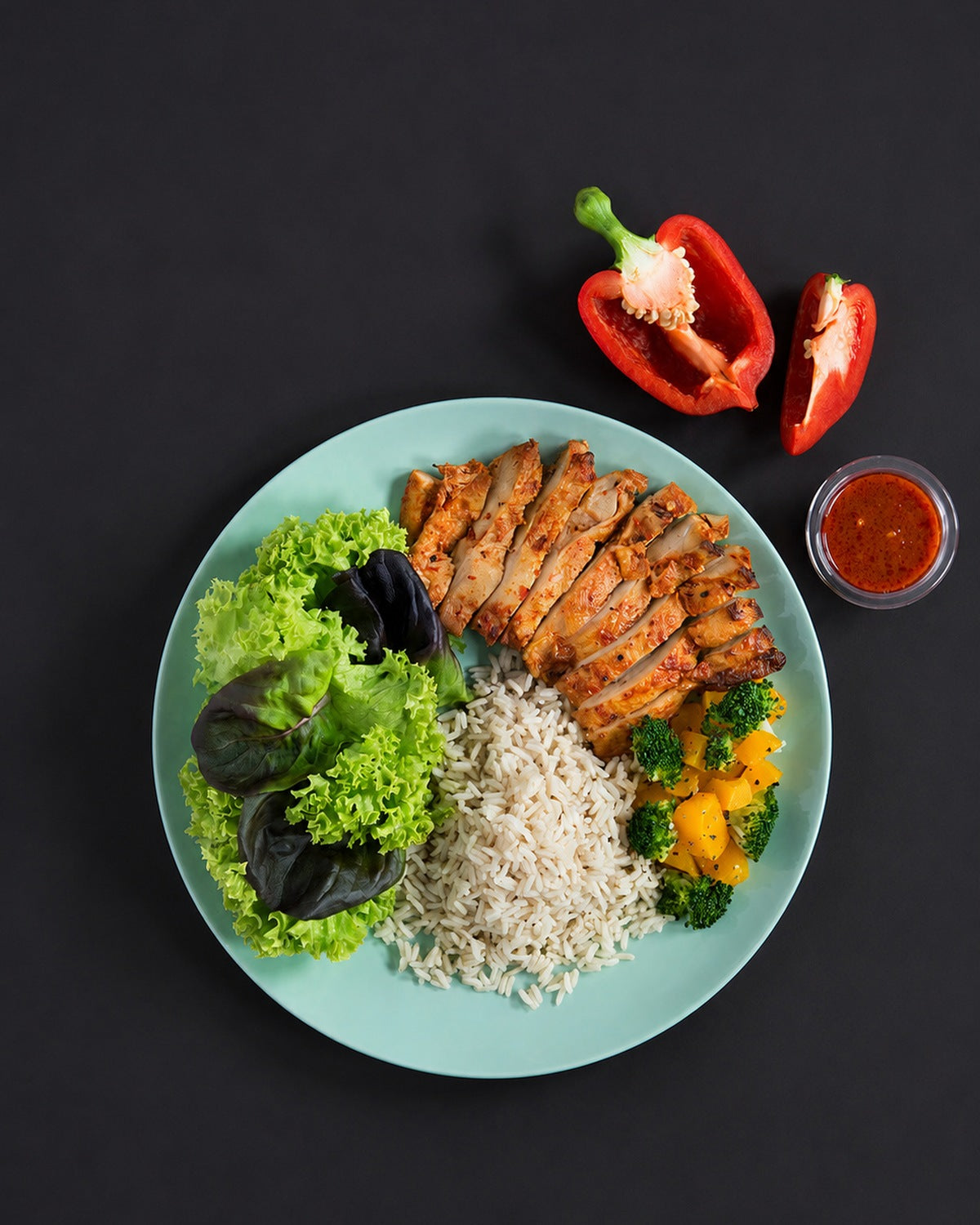 The full plate: sambal-spiced chicken breast with rice, lettuce, broccoli and pumpkin, red chilli alongside. Serving suggestion; the box is the chicken only.